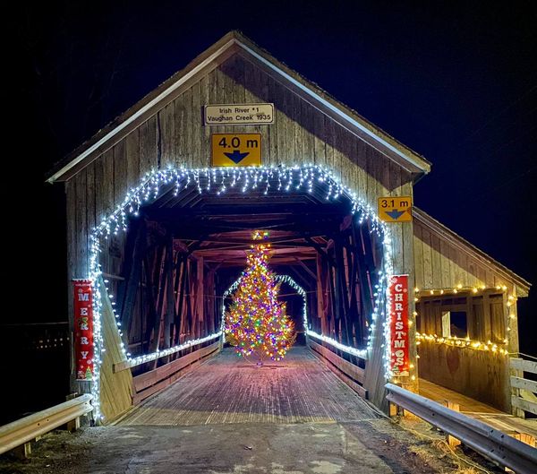 St. Martins, New Brunswick, covered bridge with Christmas tree, lit, at night